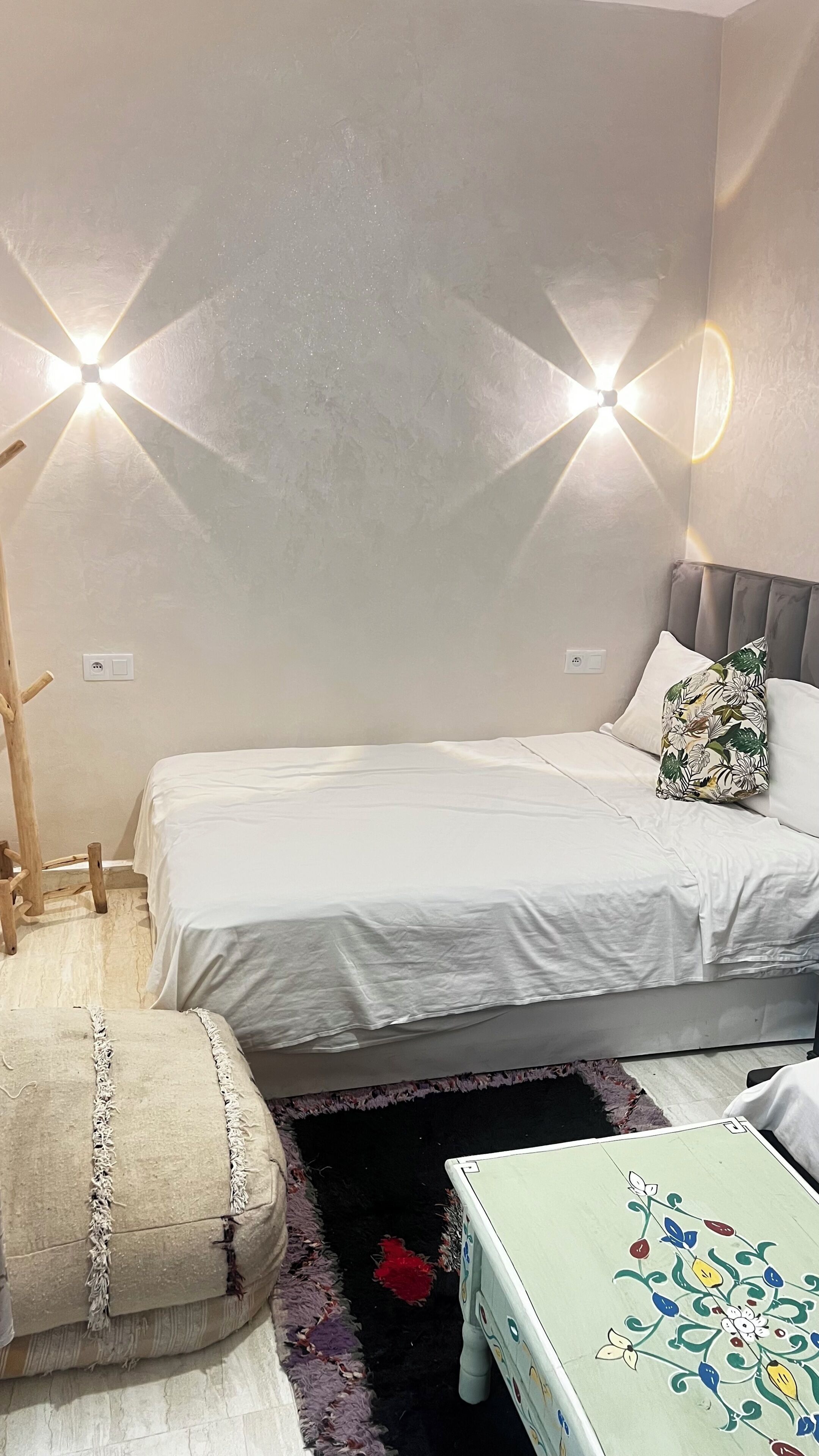 Ein Schlafzimmer mit zwei Betten, einem Holzstuhl, einem kleinen Tisch und einem dekorativen Kissen.