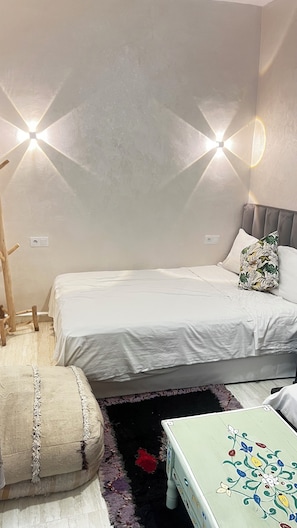 A bedroom with two beds, a wooden chair, a small table, and a decorative pillow. - Riad Dar Lokman (Marrakech)