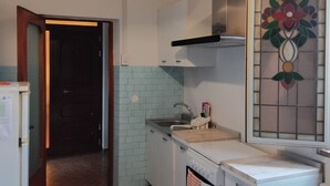Een keuken met een spoelbak, fornuis en een decoratief glas-in-lood raam.