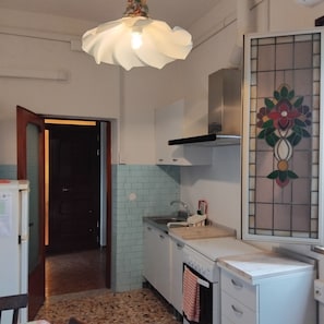 A kitchen with a sink, stove, and a decorative stained glass window.