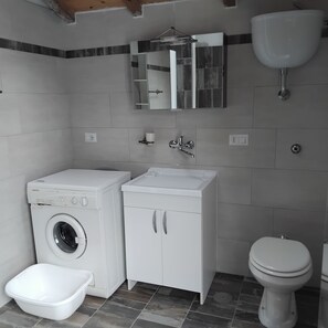 Un baño pequeño con lavadora, lavamanos, inodoro y espejo.