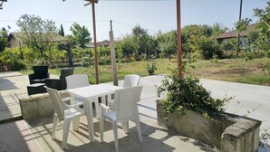 Een terras buiten met een tafel en stoelen, omgeven door groen en woongebouwen.