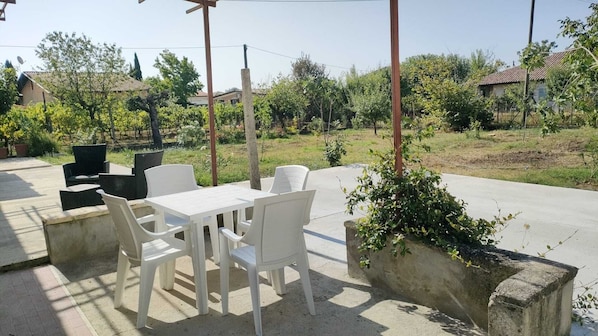 An outdoor patio with a table and chairs, surrounded by greenery and residential buildings.