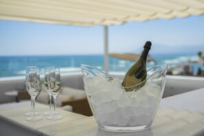 A champagne bottle in an ice bucket with two glasses beside it, overlooking a body of water. - Frontline Beach Costabella (r2576927) (Marbella)
