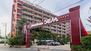 Un hotel de varios pisos con un arco de entrada llamativo y un estacionamiento.