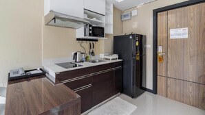 Una cocina moderna con microondas, refrigerador y teléfono sobre la encimera.