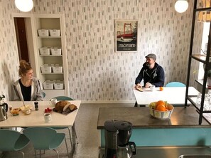 Een kamer met een behang, een koffieapparaat, een tafel met eten en een plank met dozen.