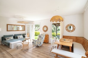 A bright living room with a sofa, a dining table, and a chair. There are two large windows and a mirror on the wall. - Tamariu - Magnificent villa with swimming pool (CT)