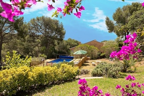 A backyard with a swimming pool, wooden deck, and a house. - Tamariu - Magnificent villa with swimming pool (CT)