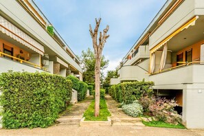 Ein Innenhof mit einem zentralen Baum, umgeben von Hecken und einem Weg.
