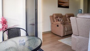 A modern living room with a glass-top table, a sofa, and a reclining chair. - Cozy 2bedroom apartment in beautiful Nairobi, wit gym,swimming pool & City views (Kangundo)
