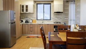 A modern kitchen with wooden cabinets, a stainless steel refrigerator, a microwave, and a gas stove. - Cozy 2bedroom apartment in beautiful Nairobi, wit gym,swimming pool & City views (Kangundo)