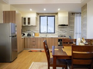 Eine moderne Küche mit Holzschränken, einem Edelstahlkühlschrank, einer Mikrowelle und einem Gasherd.