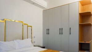 A bedroom with a bed, a wardrobe, and a nightstand. - Cozy 2bedroom apartment in beautiful Nairobi, wit gym,swimming pool & City views (Kangundo)