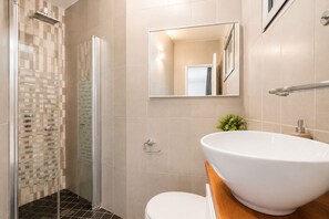 A modern bathroom with a glass shower enclosure, a white sink, and a toilet. - MAMAD Duplex & Panoramic Terrace near Beach | FeelHome (Tel Aviv - Jaffa)