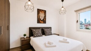 Una camera da letto con un letto, due comodini, una lampada da comodino, una finestra con vista sulla città e due lampade a sospensione.