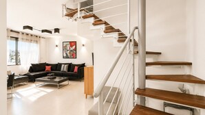 Un soggiorno moderno con una scala, un divano nero, un tavolino da caffè e un quadro appeso al muro.