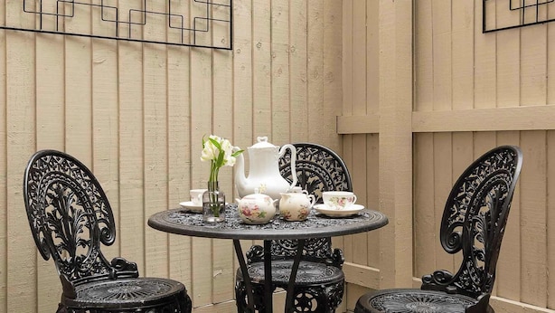A round table with four ornate chairs, a white pitcher, teacups, and a vase with flowers. - The Monmouth House of Bath (Bath)