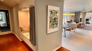 A modern interior with a dining area, a seating area with a sofa and curtains, and a patterned rug on the floor. - 4 Star Holiday Home in Nykobing Sj (Nykobing Sjaelland)