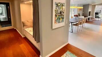 Un interior moderno con zona de comedor, un área de estar con sofá y cortinas, y una alfombra estampada en el suelo.