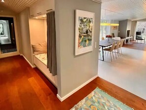 Ein modernes Interieur mit Essbereich, einer Sitzecke inklusive Sofa und Vorhängen, sowie einem gemusterten Teppich auf dem Boden.