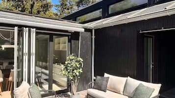 Un patio moderno al aire libre con sofá, sillas y una mesa.