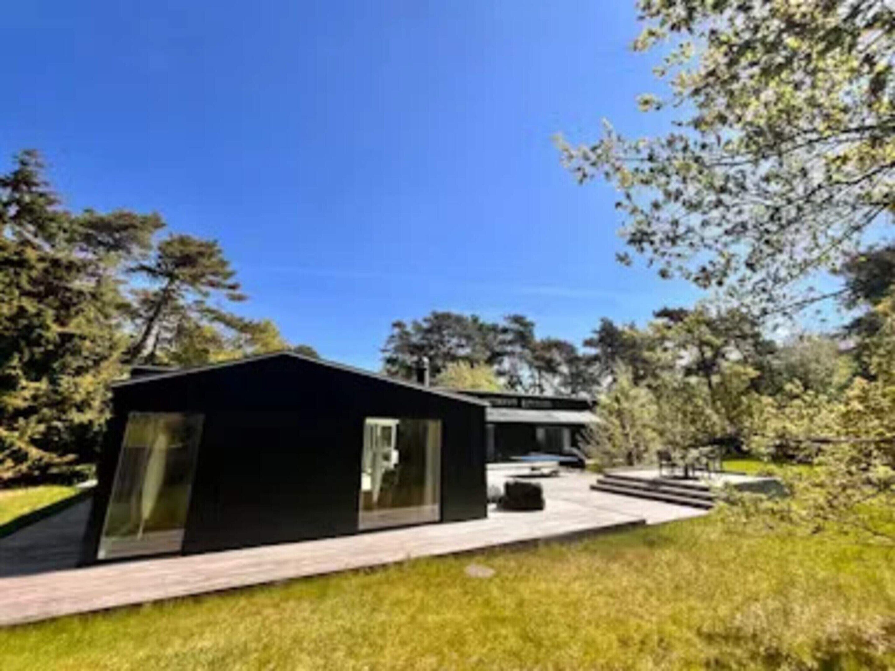 A modern building with a flat roof, large windows, and a paved pathway leading to it.