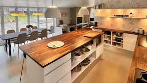 A modern kitchen with a wooden island, white cabinetry, and pendant lighting. - 4 Star Holiday Home in Nykobing Sj (Nykobing Sjaelland)