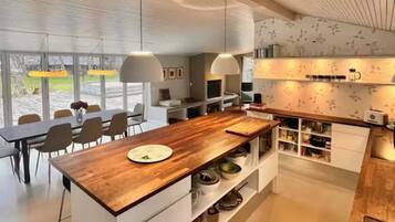 Una cocina moderna con una isla de madera, armarios blancos e iluminación colgante.
