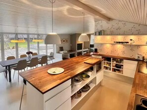 Eine moderne Küche mit einer Holztischinsel, weißen Schränken und Pendelleuchten.