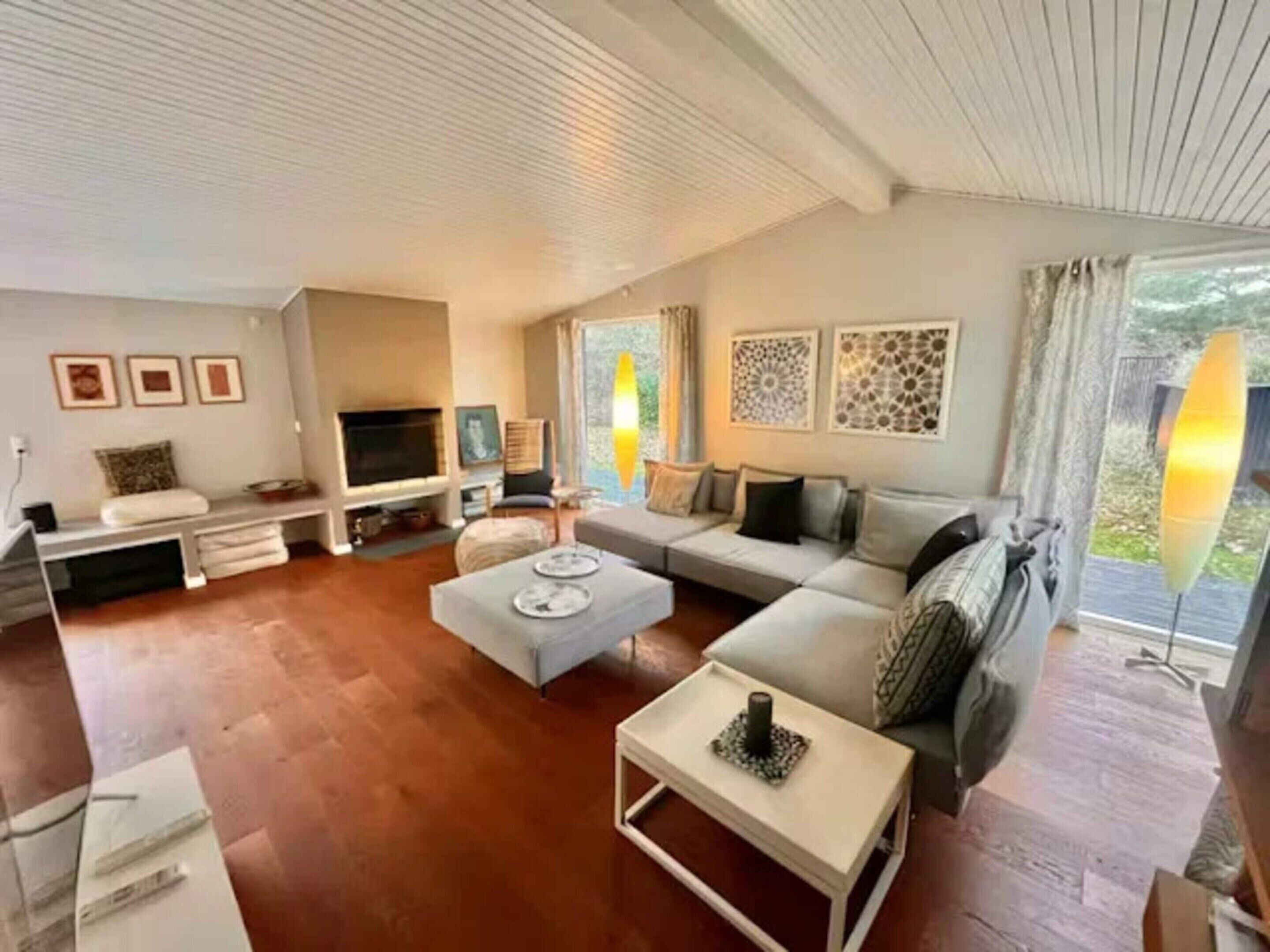 Una sala de estar con un sofá, una mesa de centro, un televisor y obras de arte en las paredes.