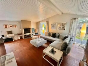 Ein Wohnzimmer mit einer Couch, einem Couchtisch, einem Fernseher und Kunstwerken an den Wänden.