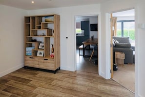 Ein modernes Interieur mit einer Holzbücherreih, einem Essbereich und Blick ins Freie.