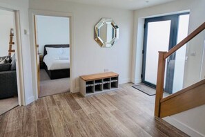 A hallway with a bed, a bench, and a mirrored wall. - Coome Lodge: Modern Stay near Saunton Sands Beach (Braunton)