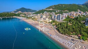 An aerial view of a coastal city with a beach, buildings, and a mountainous backdrop. - Status M Apartments 152 (Becici)