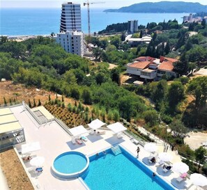 A pool area with a rectangular pool, lounge chairs, and umbrellas. - Status M Apartments 152 (Becici)