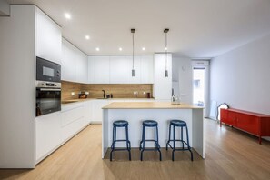 Een moderne keuken met witte kastjes, een houten aanrecht en een centraal kookeiland met krukken.