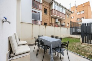 Un patio con una mesa y sillas, un sofá y una reja.