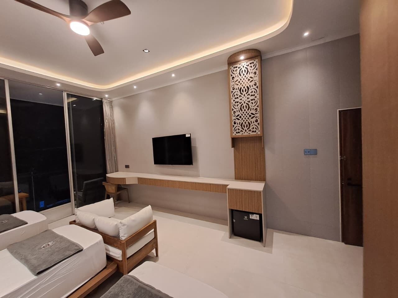 Una moderna camera d'hotel con divano, televisore, scrivania e pannello decorativo a parete.