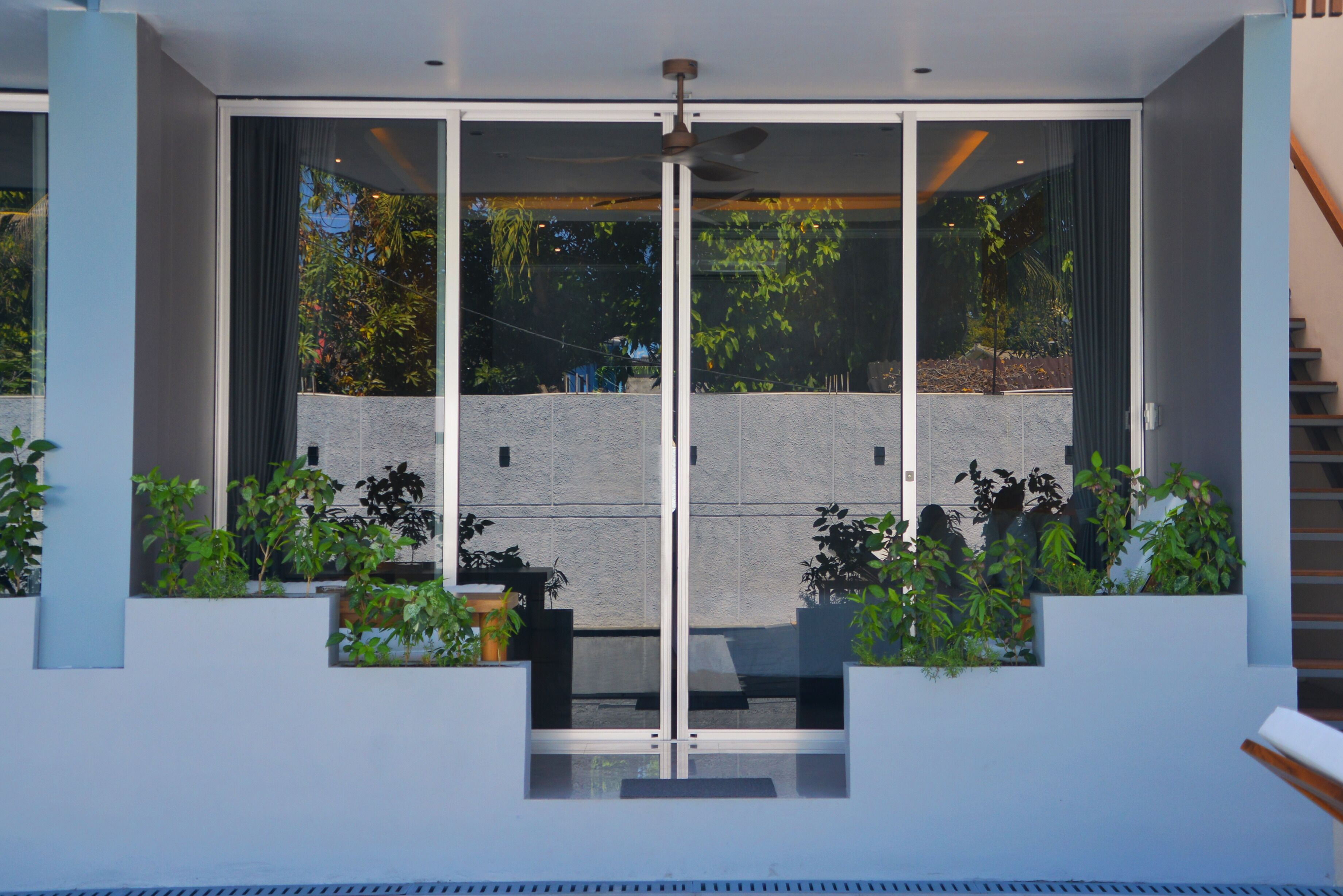 Un bâtiment moderne doté d’une façade en verre, d’une entrée centrale et entouré de verdure.