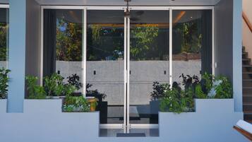 A modern building with a glass facade, a central entrance, and surrounding greenery.