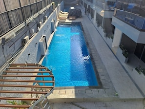 Una piscina con cubierta de madera, rodeada de edificios.