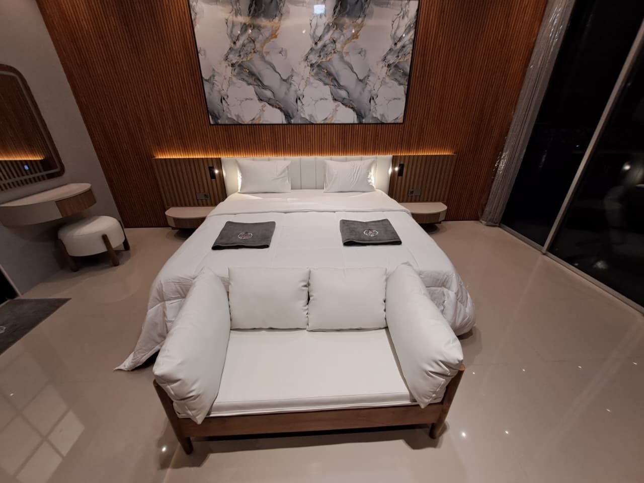 Et moderne soveværelse med en stor seng, en sofa og en væg i marmor.