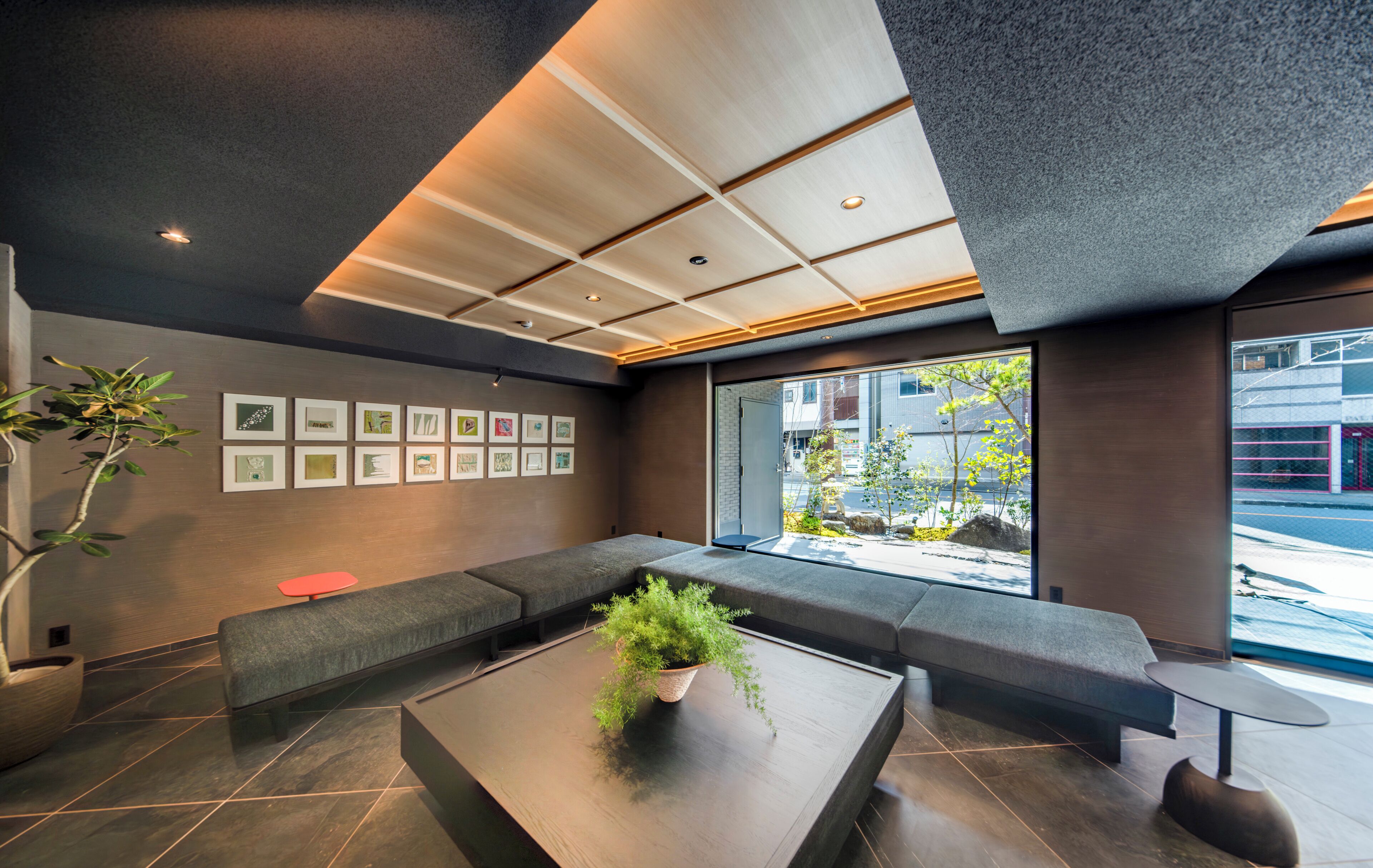 Ein modernes Interieur mit einer Sitzecke, einem Couchtisch mit einer Pflanze und gerahmten Bildern an der Wand.
