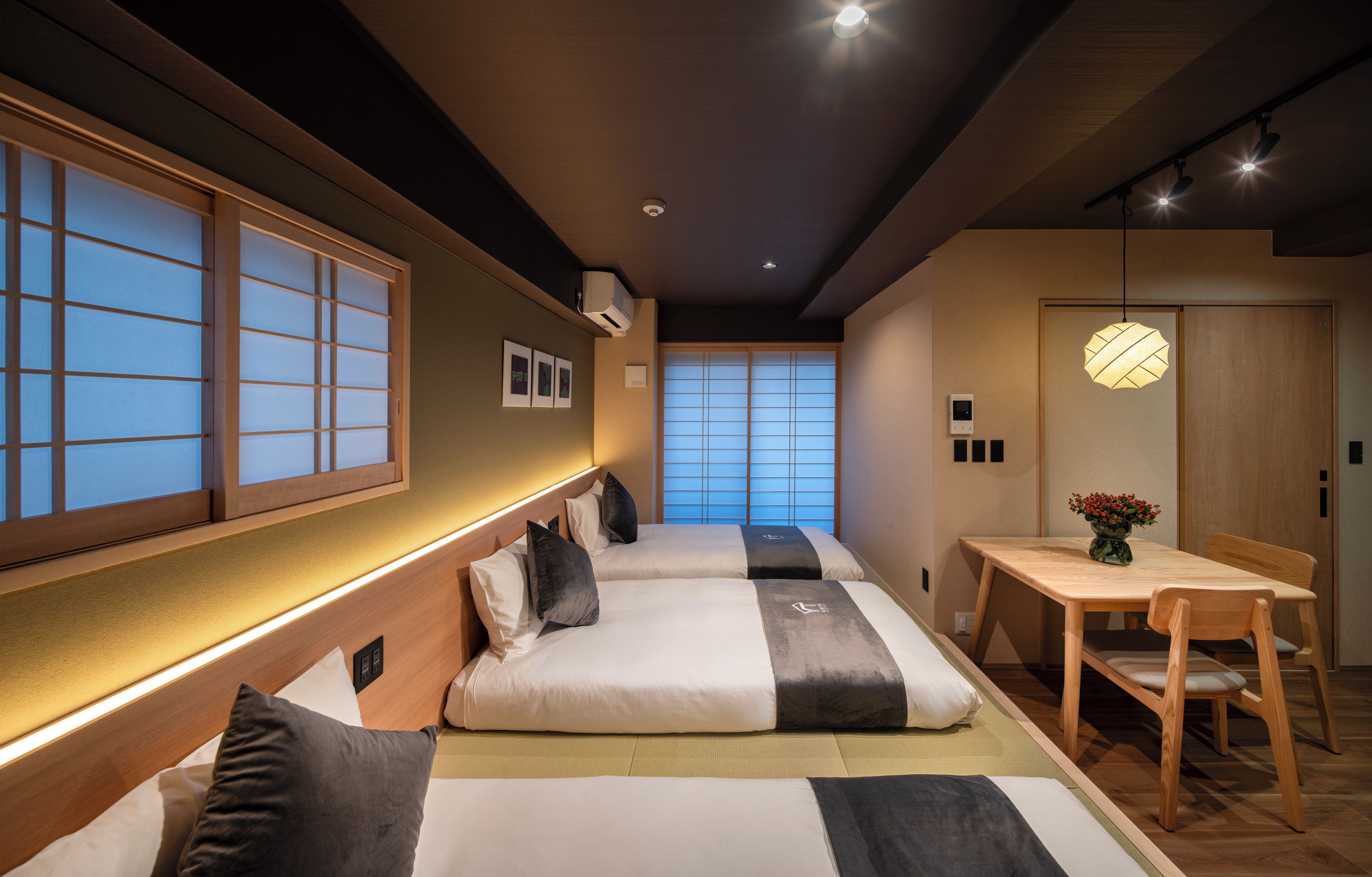 Ein Hotelzimmer im traditionellen japanischen Stil mit Tatami-Böden, Shoji-Schirmen und einem niedrigen Holztisch mit Stühlen.