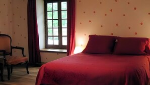 Een kamer met een bed, een raam met gordijnen, een stoel en een wand met een patroon.