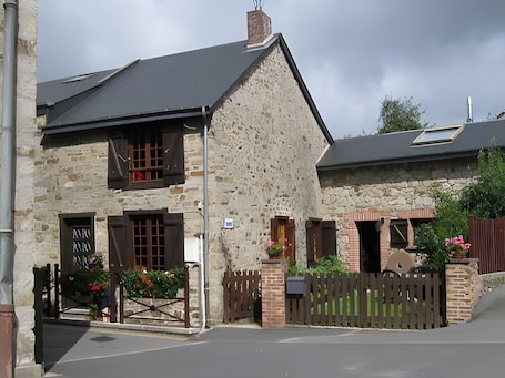 A stone building with a sloped roof, a wooden gate, and a small garden with flowers.. Charming Watermill Cottage