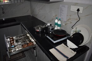 A kitchen with a built-in stove, a microwave, and a sink. There are two bottles of Bisleri water on the counter.