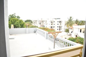 Une terrasse sur le toit, dotée d’une balustrade blanche, d’une pergola en bois et offrant une vue sur les immeubles d’habitation.