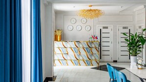 A hotel lobby with a marble reception desk, a chandelier, a dining area with a glass table, and a potted plant. - Astoria Boutique (Tashkent)
